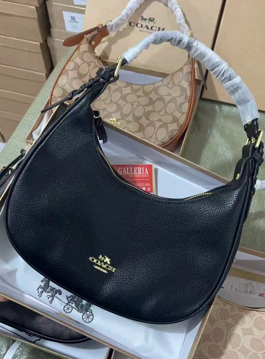 Black Coach handbag on a white surface with a blurred background