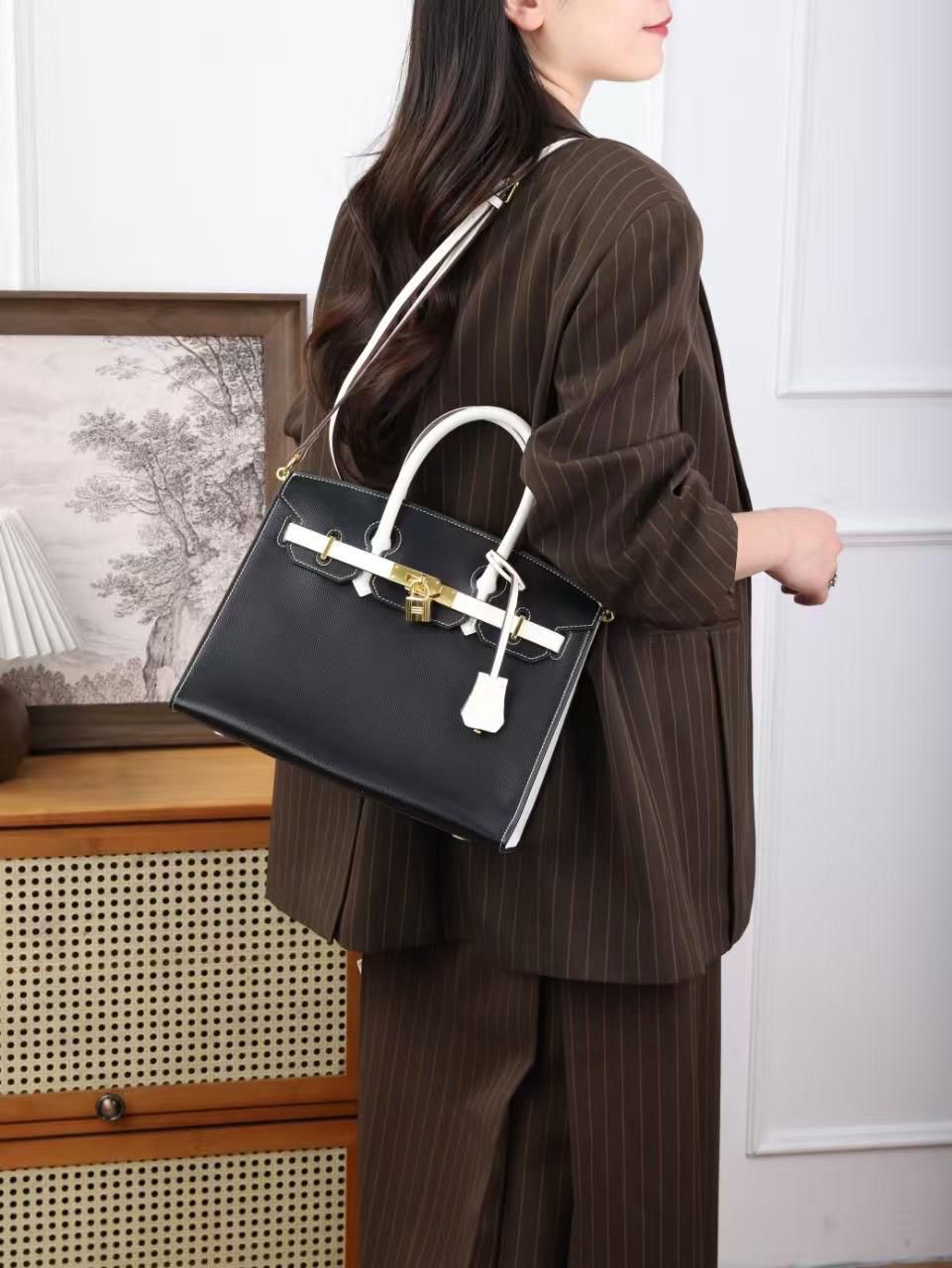 Model carrying classic black designer leather shoulder handbag