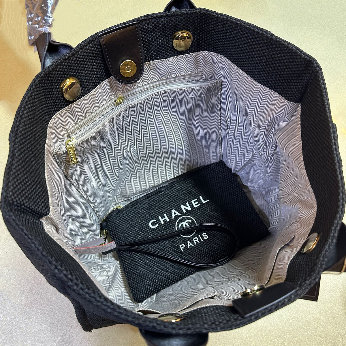 Black handbag with a Chanel pouch inside on a light background