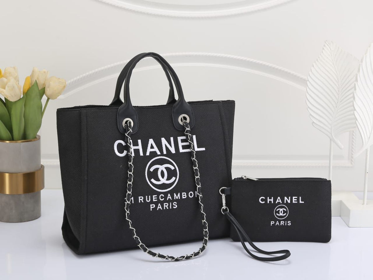 Black Chanel handbag with matching pouch on a white surface with decorative elements.