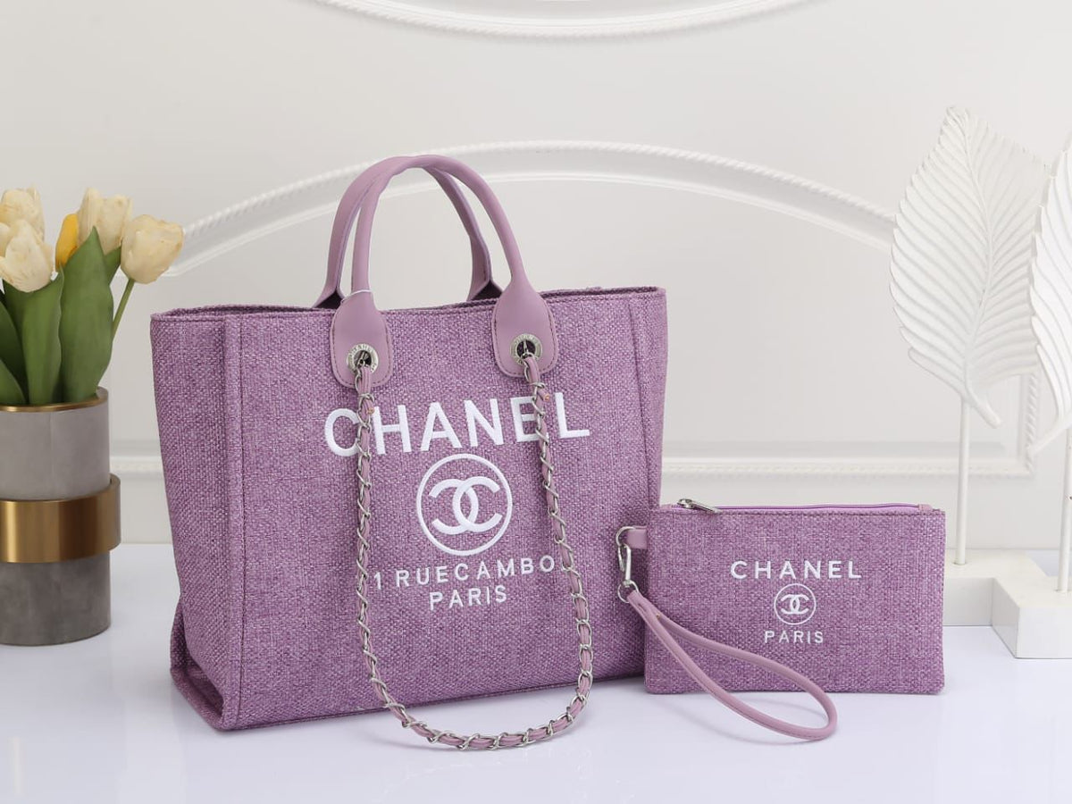 Purple Chanel handbag and matching pouch on a white surface with flowers in the background