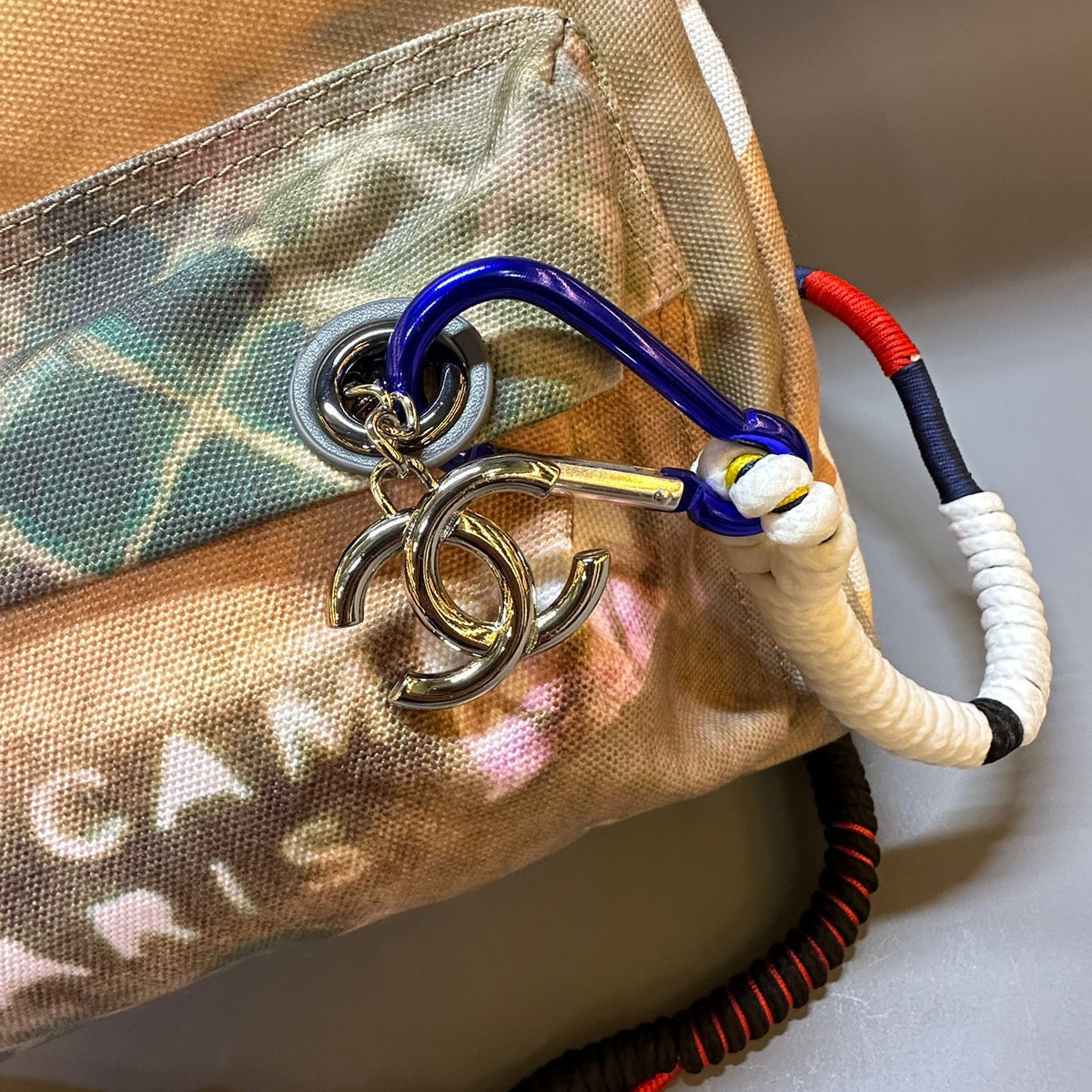 Chanel handbag with a colorful carabiner and keychain on a neutral background