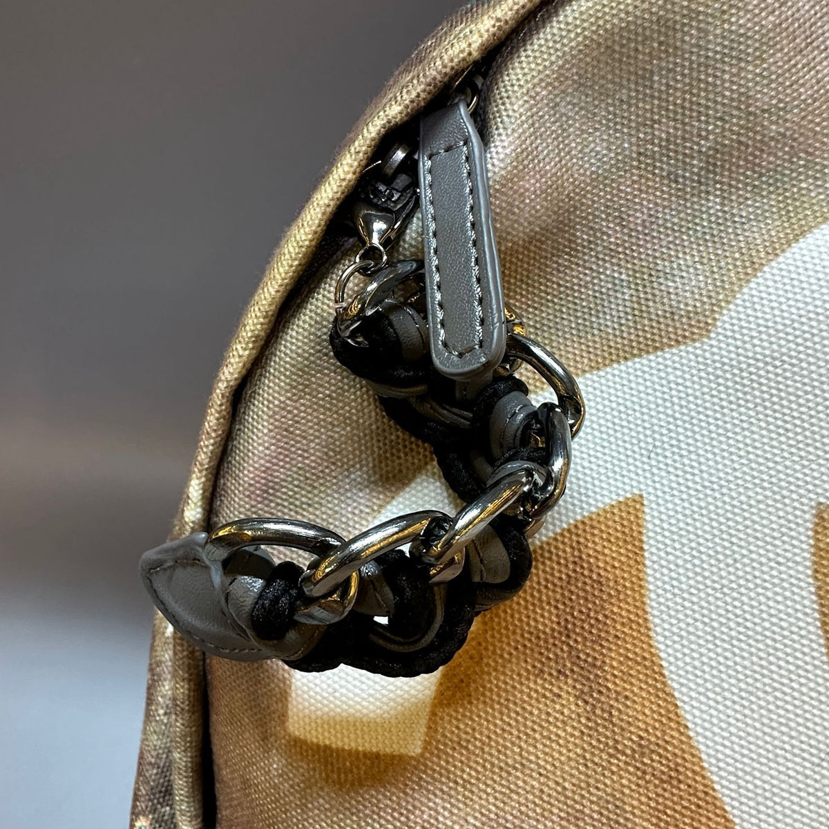 Close-up of a chain detail on a bag with a neutral background