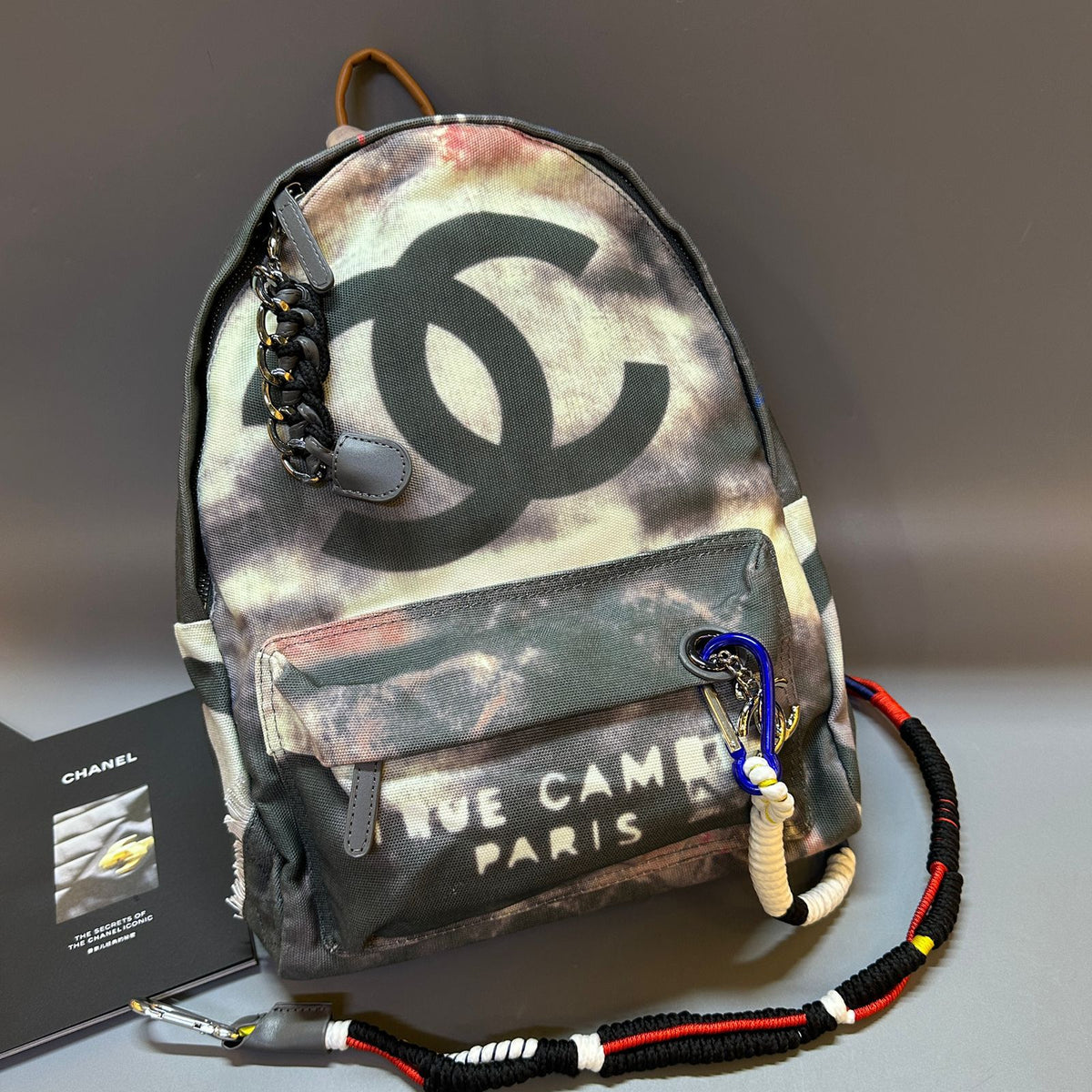 Backpack with Chanel logo and camouflage pattern on a gray surface