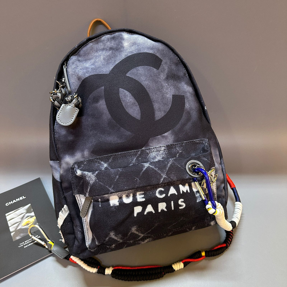 Backpack with Chanel logo and 'Rue Cam Paris' text on a neutral background