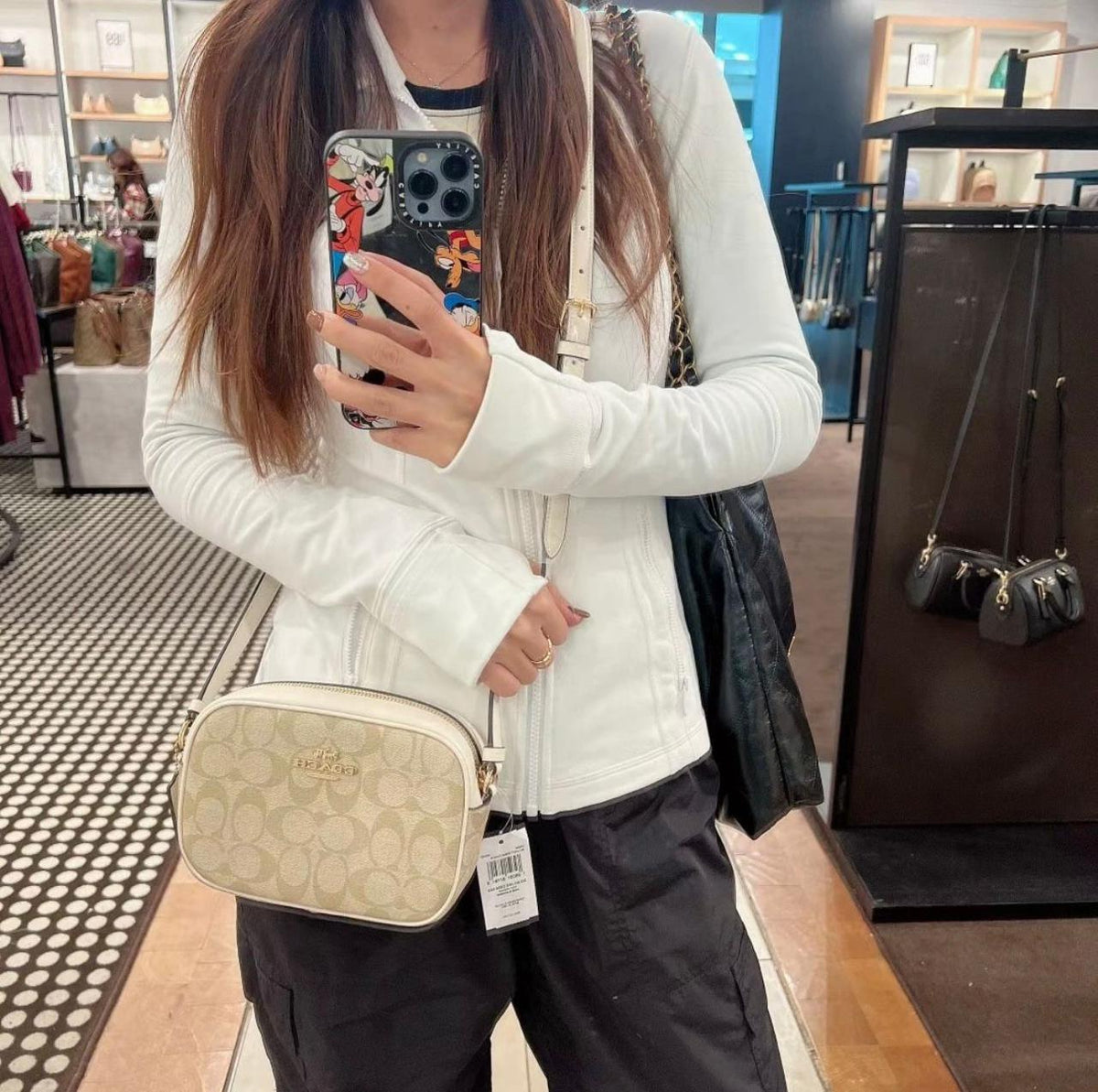 Model carrying cream Coach signature camera crossbody bag with white top