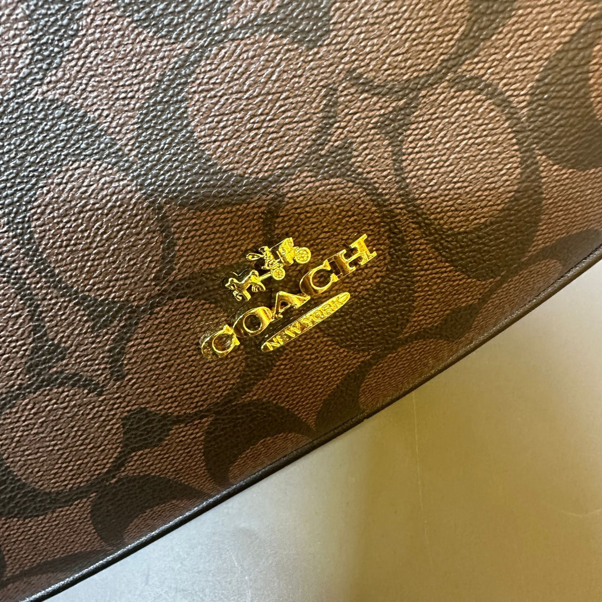 Close-up of a Coach wallet with logo on brown leather
