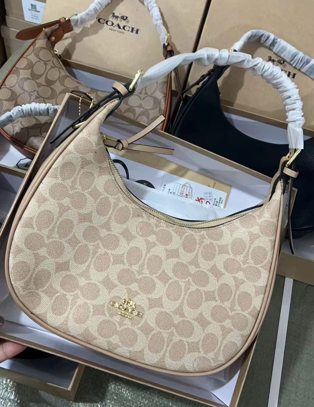Beige handbag with brand logo on a light gray surface
