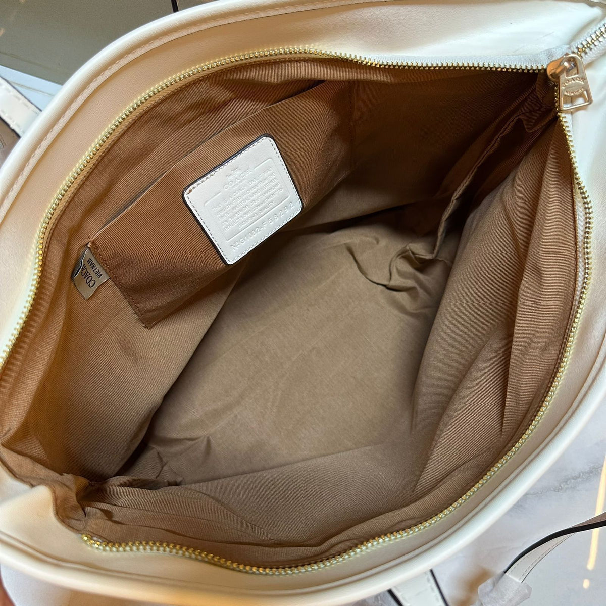 Spacious lining and authentic Coach leather patch inside signature tote bag