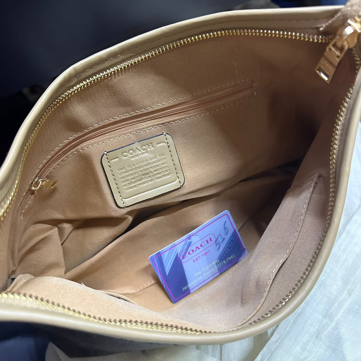 Open interior compartment view of Coach women shoulder bag with lining