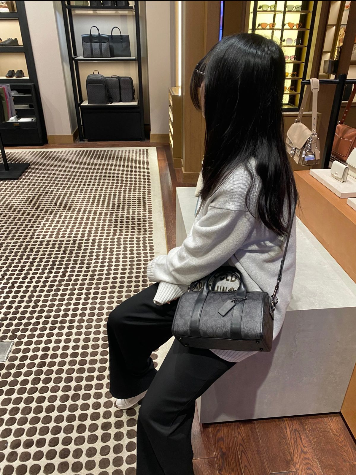 Woman carrying Coach style black women's handbag with shoulder strap