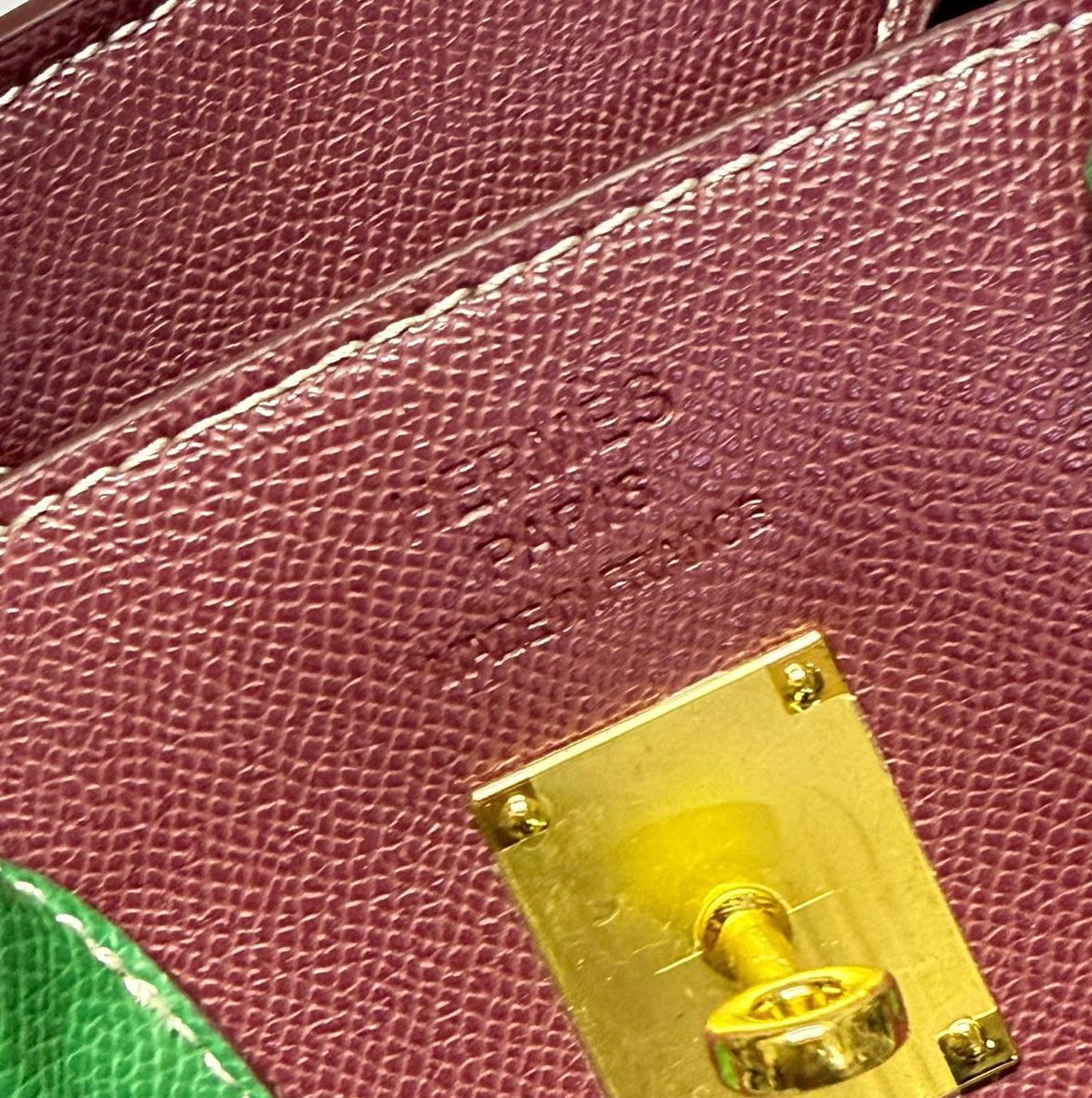 Close up of premium gold turn lock hardware on burgundy textured leather