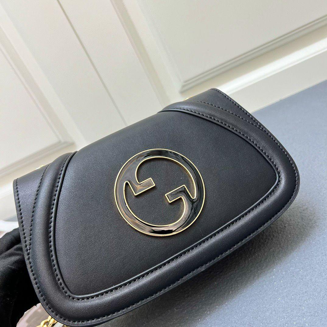Close up of gold metal interlocking G emblem on black Gucci flap bag