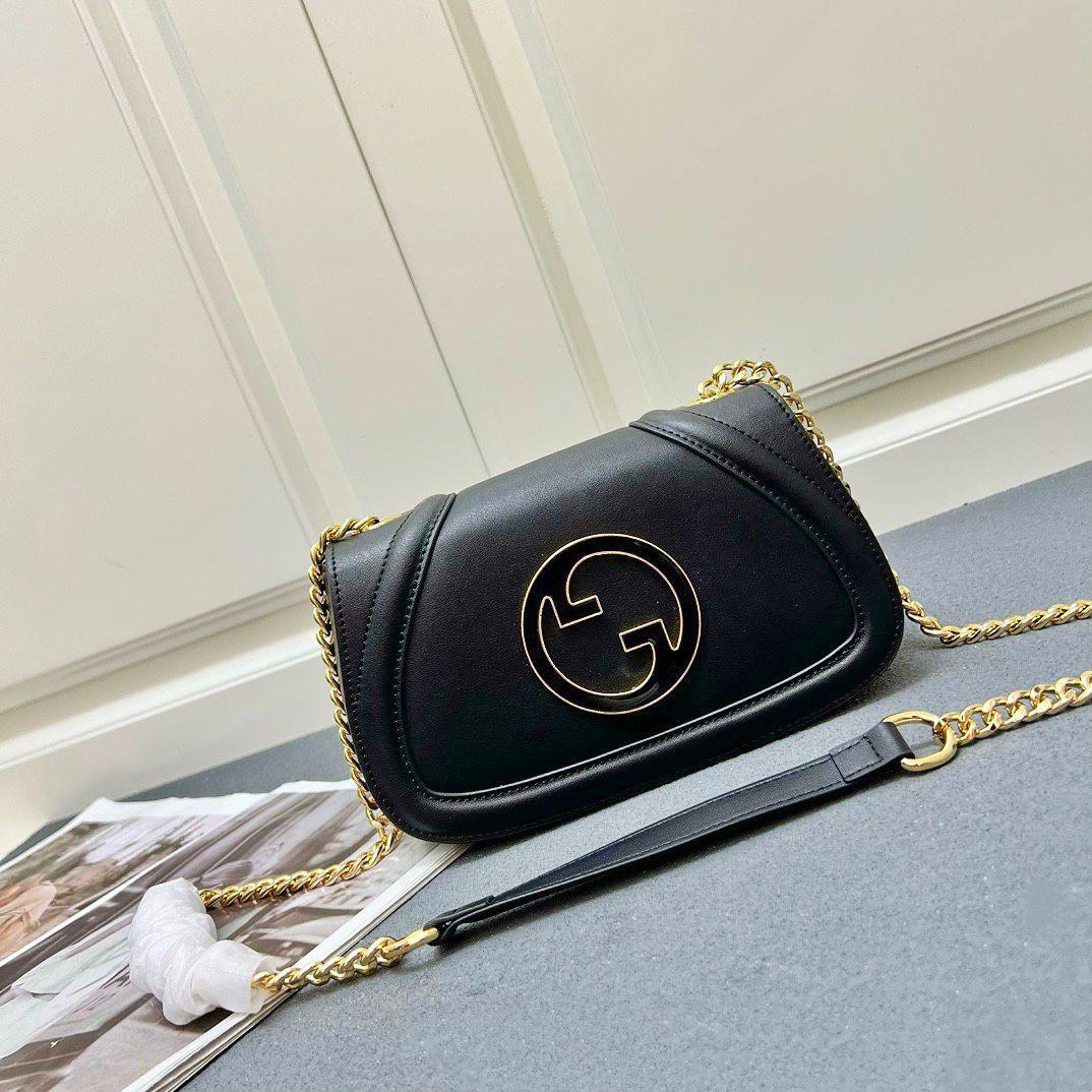 Gucci black leather shoulder bag with gold chain strap on grey background
