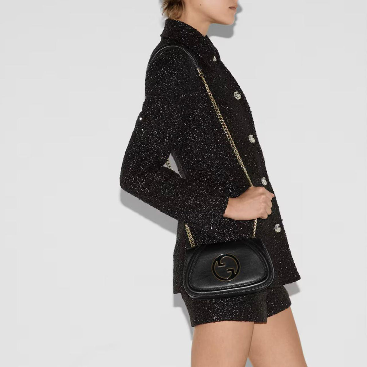Model wearing black Gucci leather crossbody bag with chain strap and black blazer