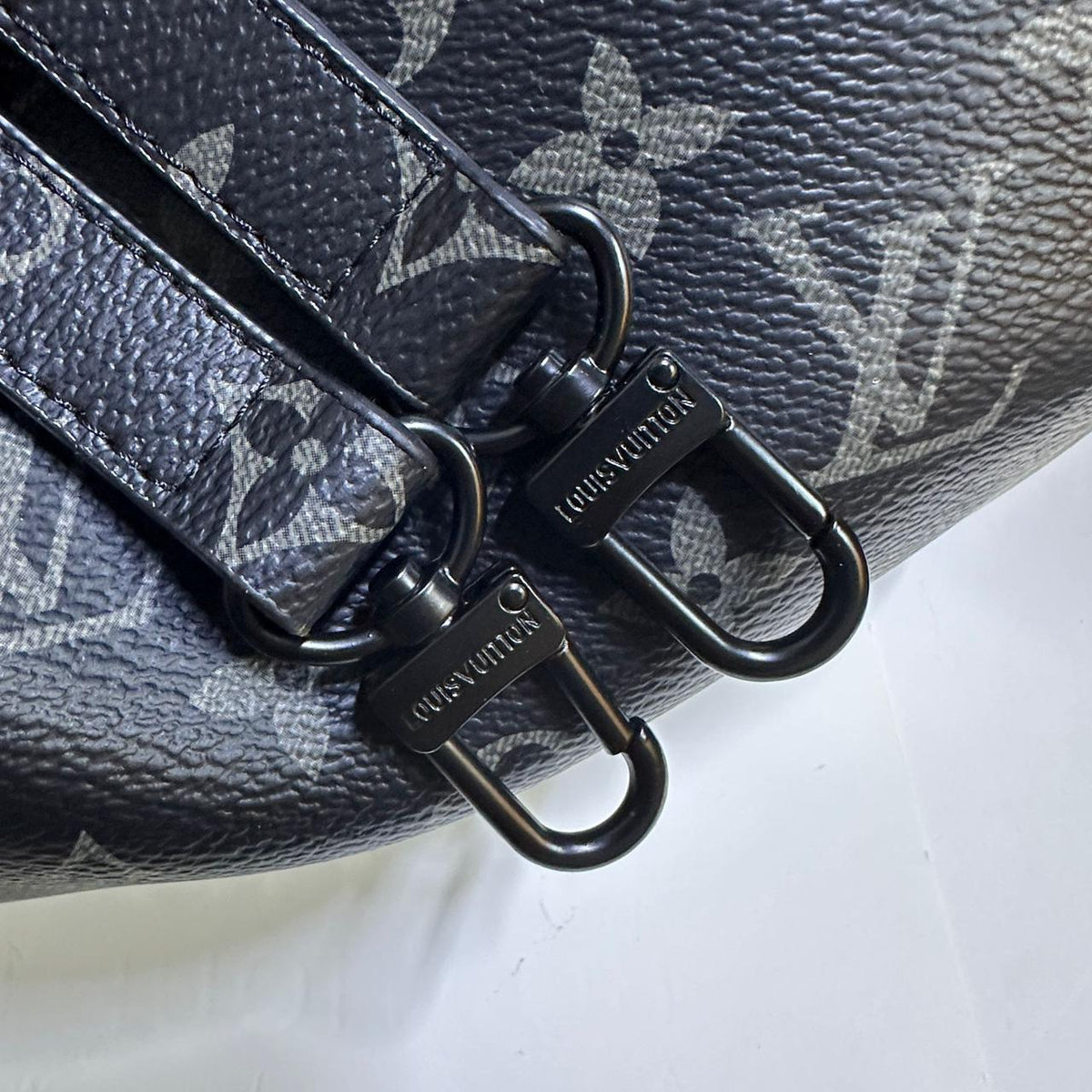 Detailed shot of double metallic zipper pulls on black monogram canvas