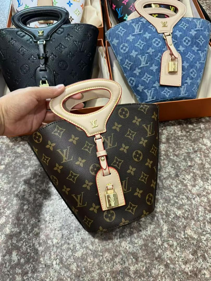 Louis Vuitton handbag with monogram pattern and gold lock, held by a hand.
