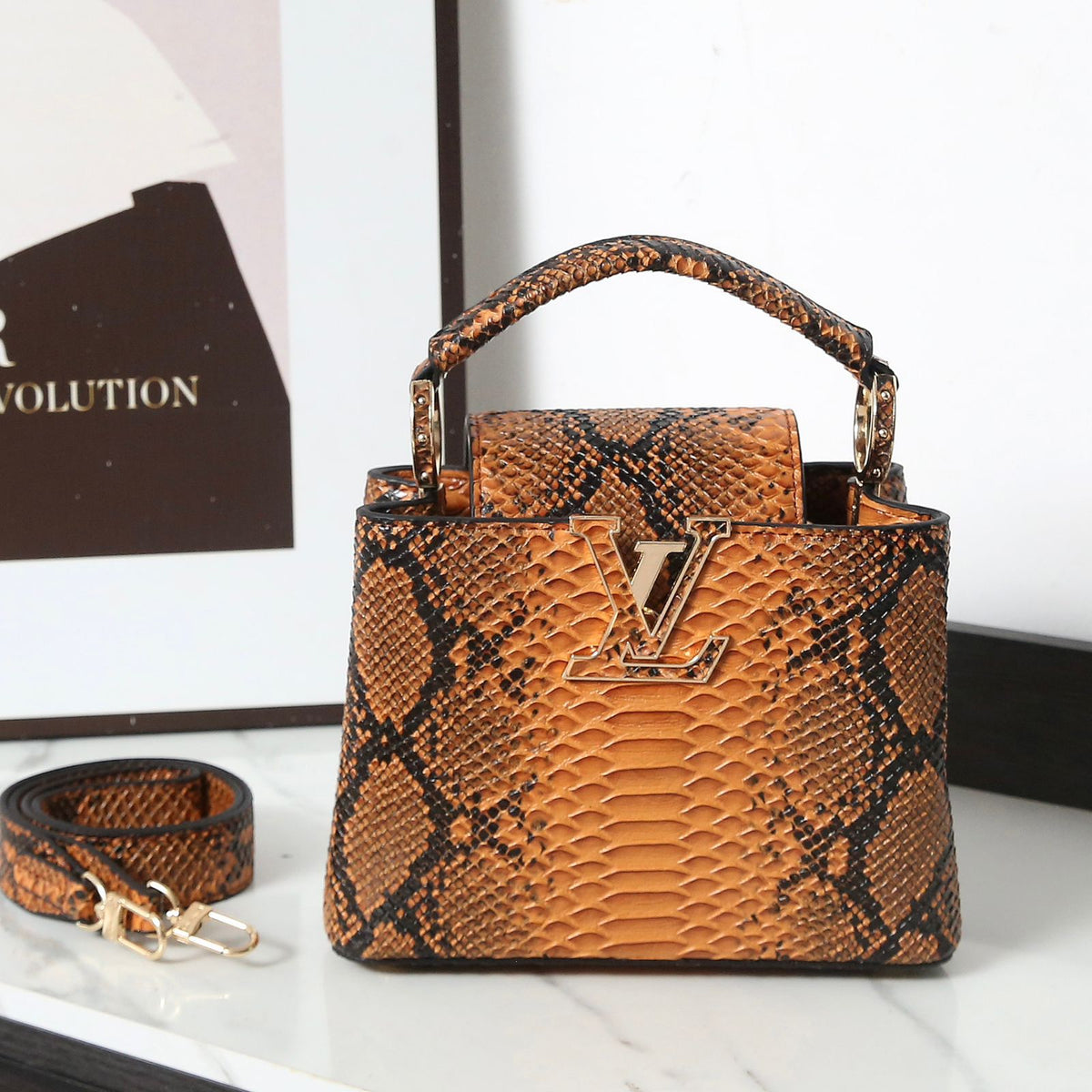 Brown snake skin pattern handbag with gold accents on a white surface.