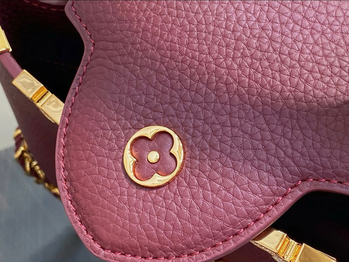 Close-up of a pink handbag with gold accents on a gray background