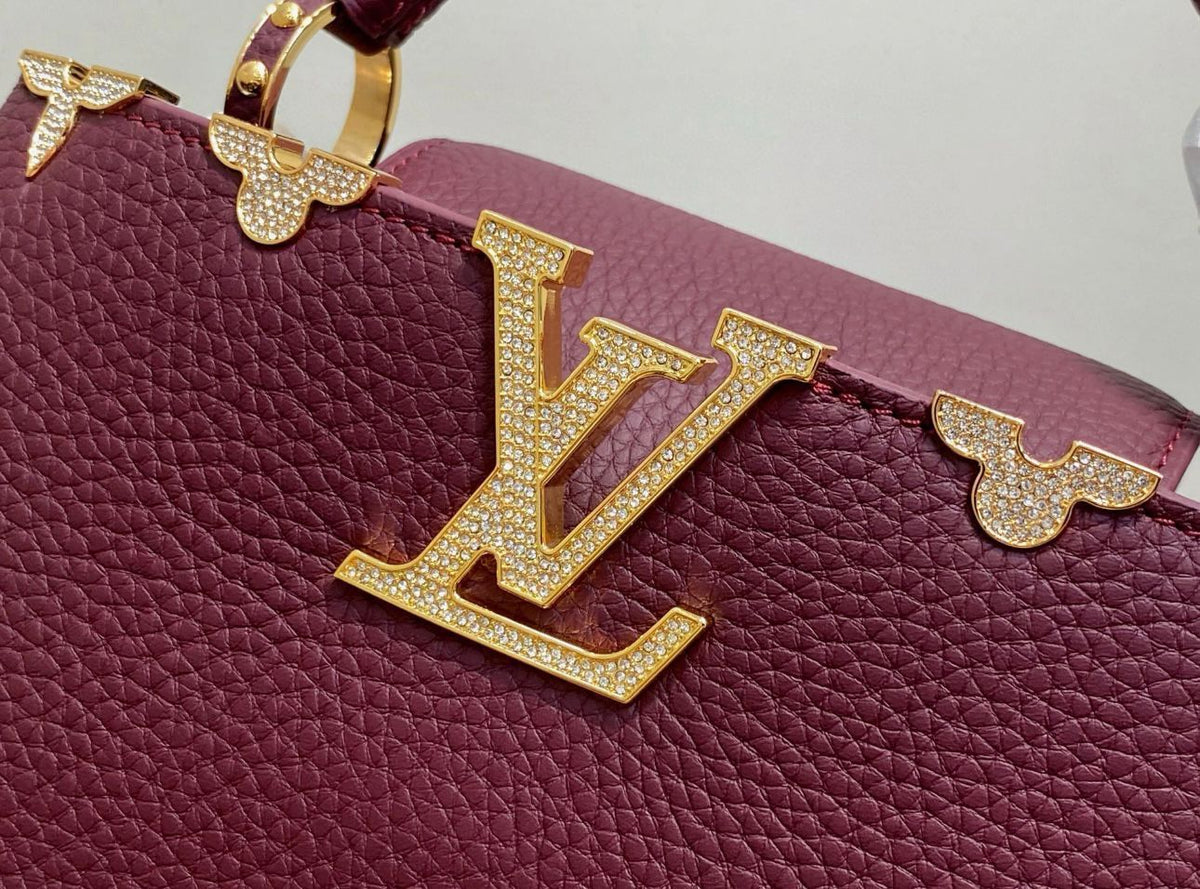 Close-up of a maroon handbag with gold embellishments featuring the Louis Vuitton logo.