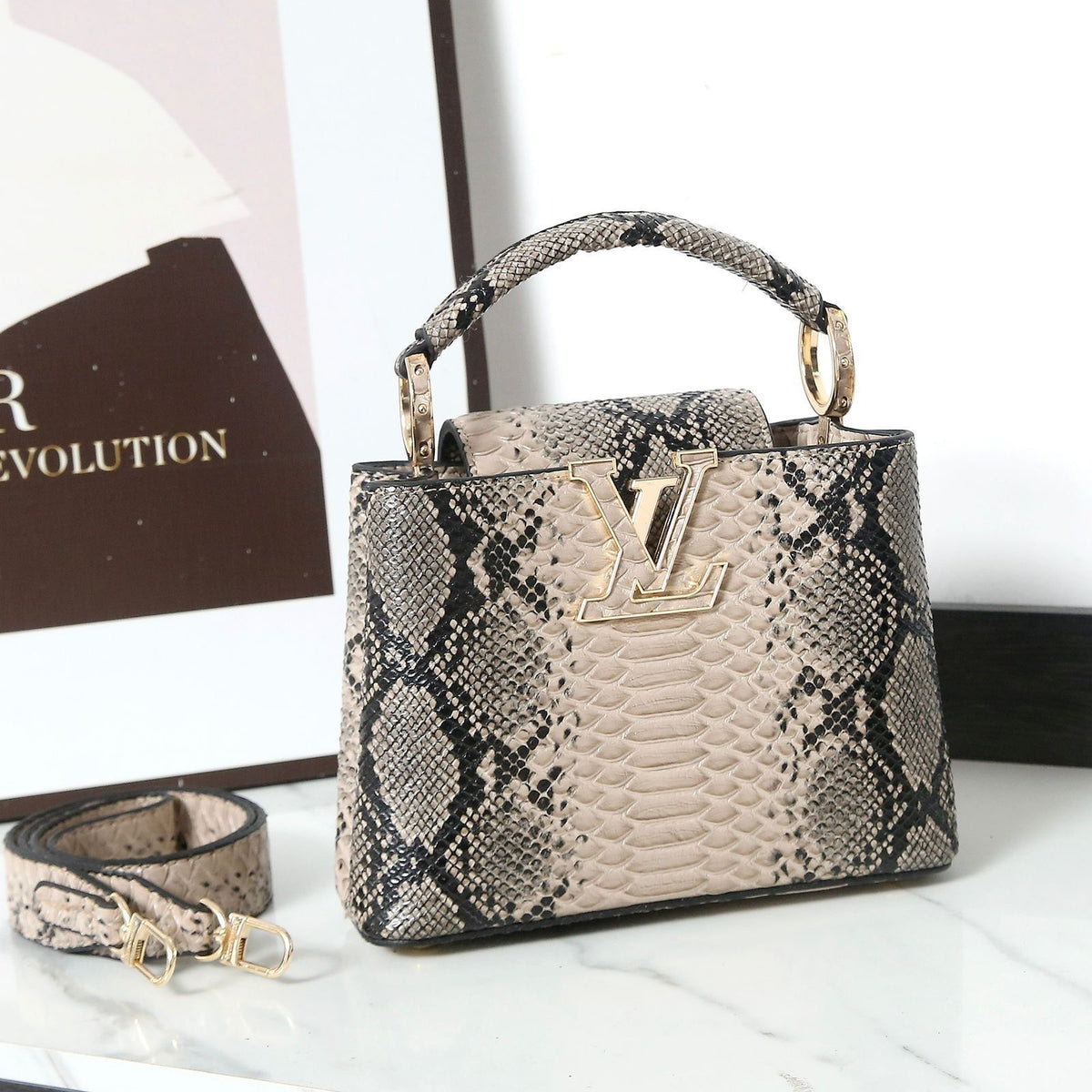 Designer handbag with snake skin pattern and visible brand logo on a white surface.