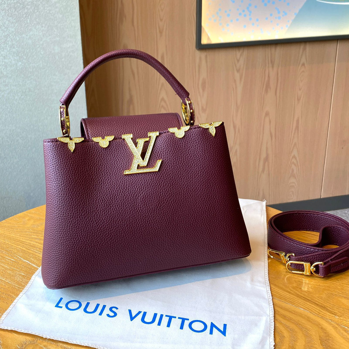 Maroon handbag with gold accents on a Louis Vuitton pouch