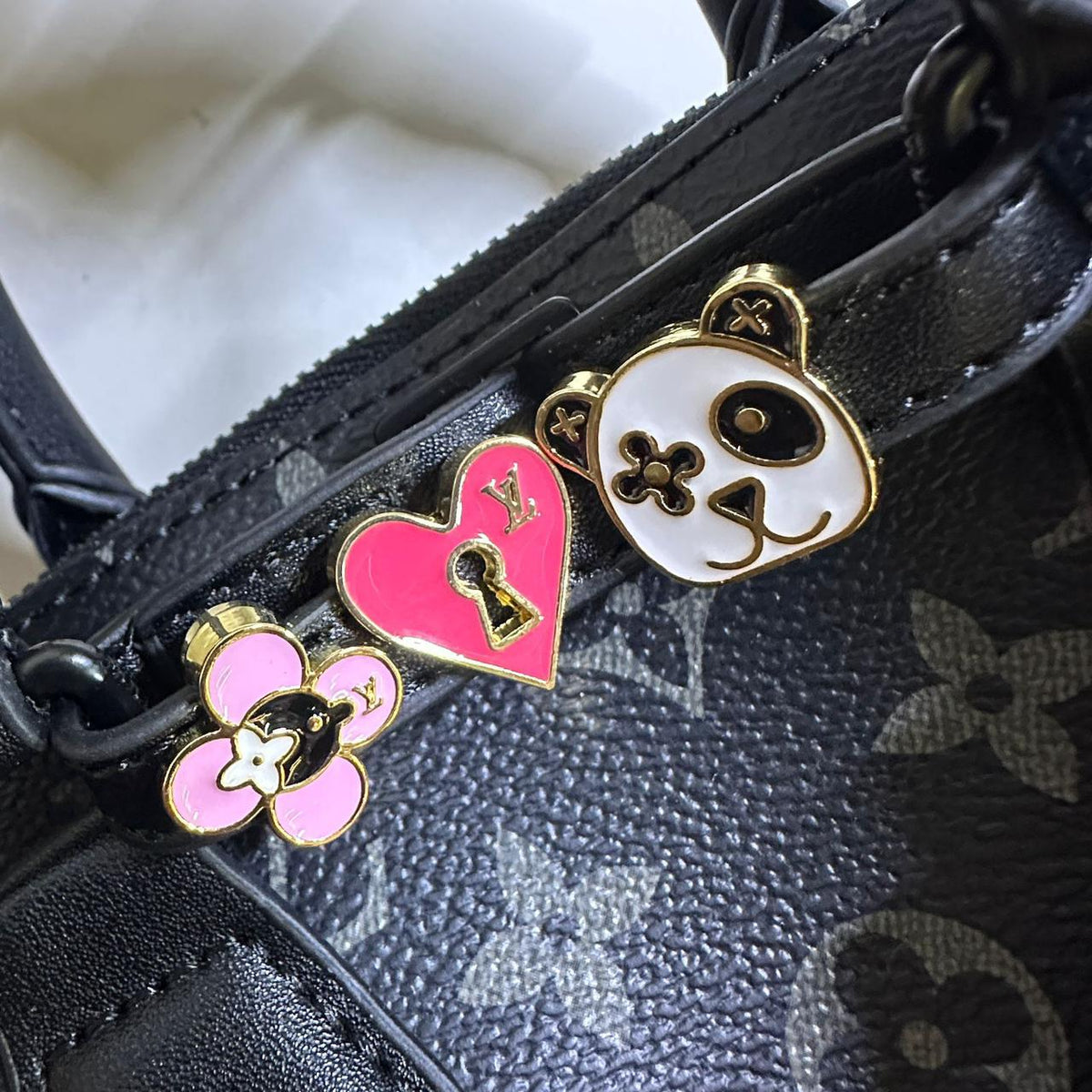 Close up of heart and panda enamel bag charms attached to Louis Vuitton purse