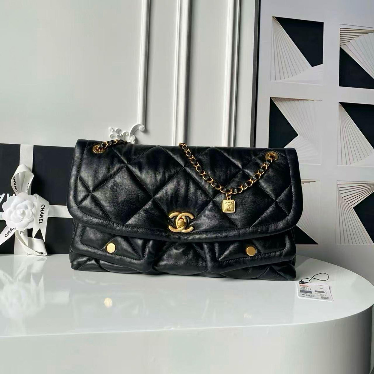 Front angle view of black quilted leather flap bag with gold chain strap