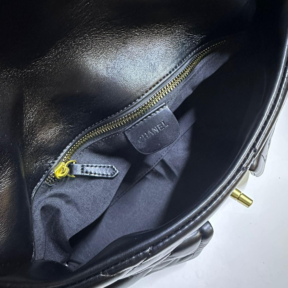 Interior lining compartment and zippered pocket view of black quilted leather flap bag