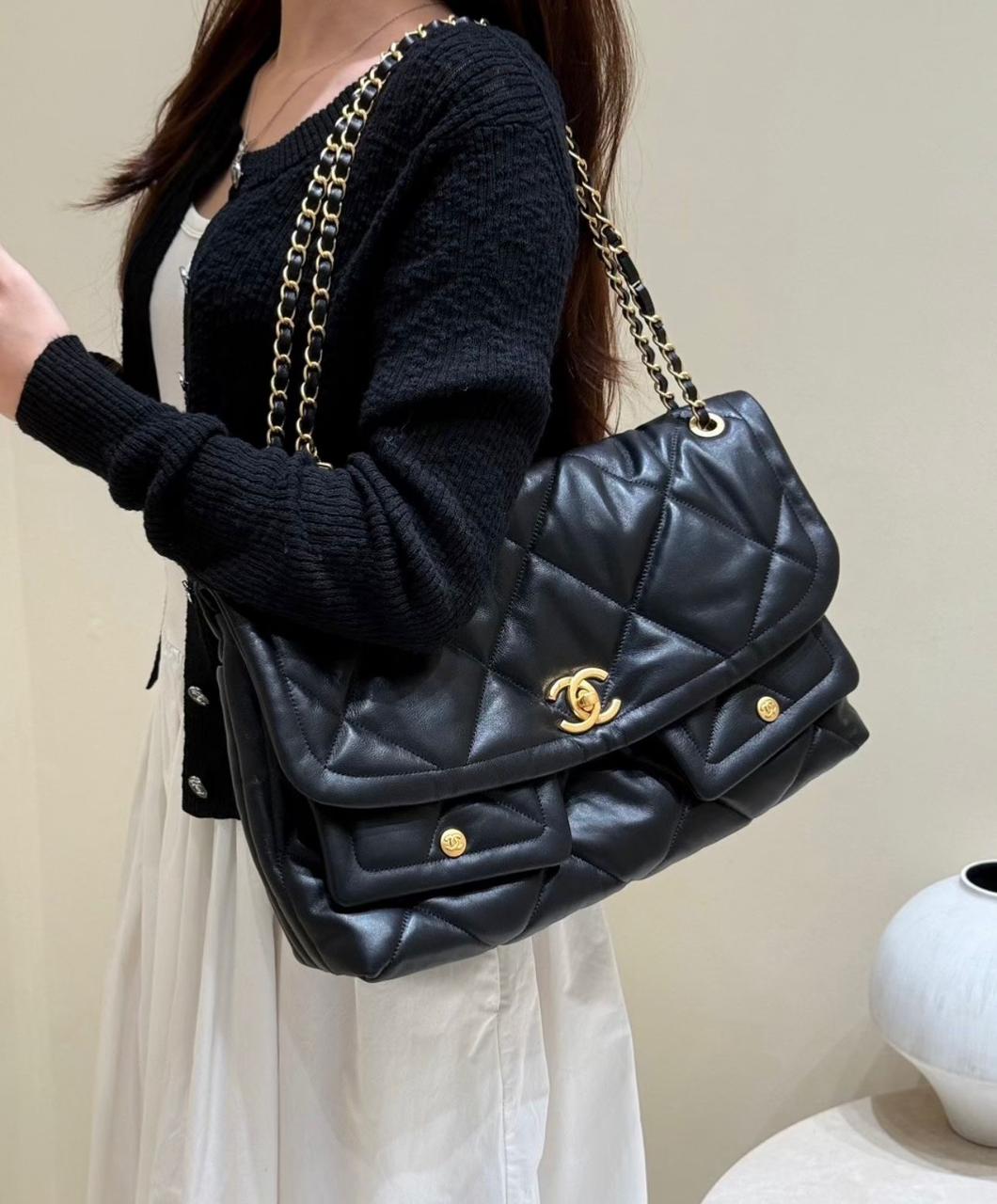 Model wearing black cardigan holding luxury black quilted leather flap shoulder bag
