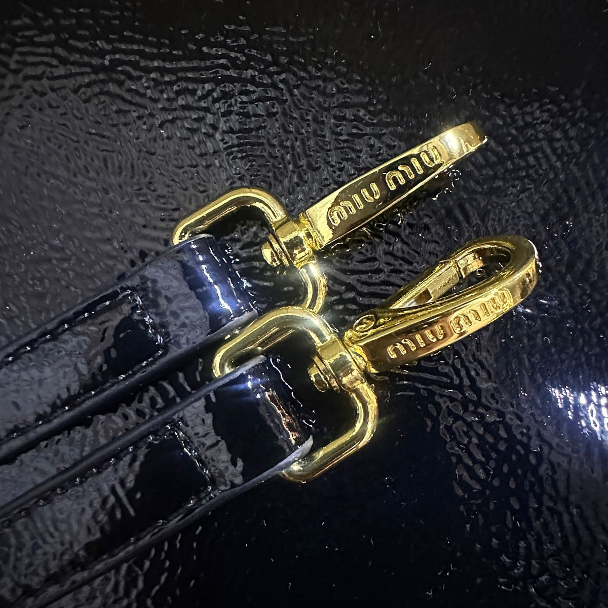 Close up of gold tone clips and strap hardware on Miu Miu tote bag