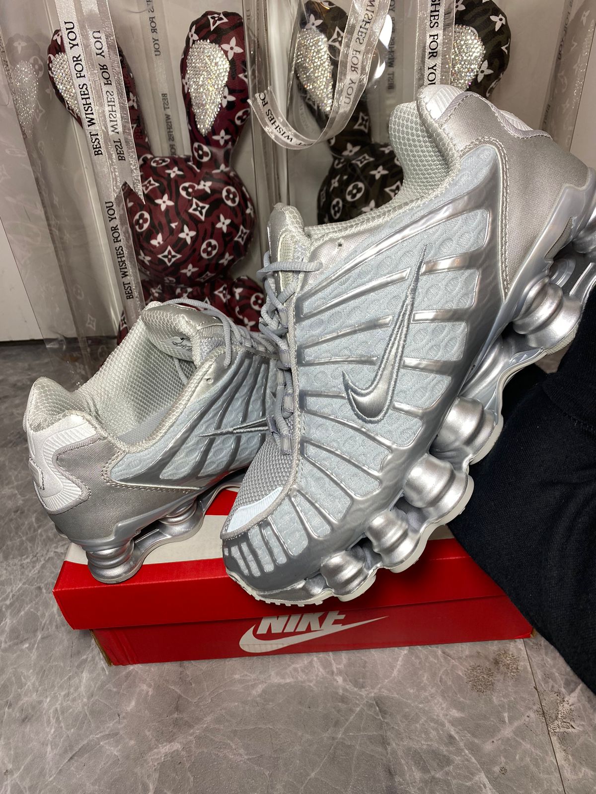 Nike Shox TL women’s White and Metallic Silver shoe held in hand