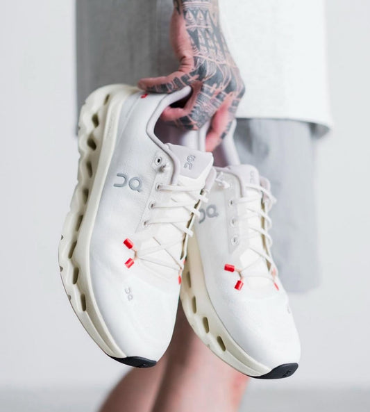 On Cloudtilt women’s White and Ivory shoes held in hand