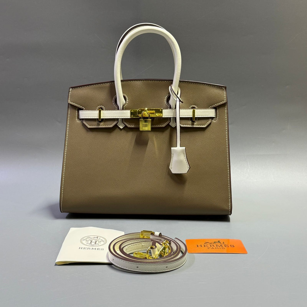 Taupe khaki luxury leather handbag with white handles and gold key clochette