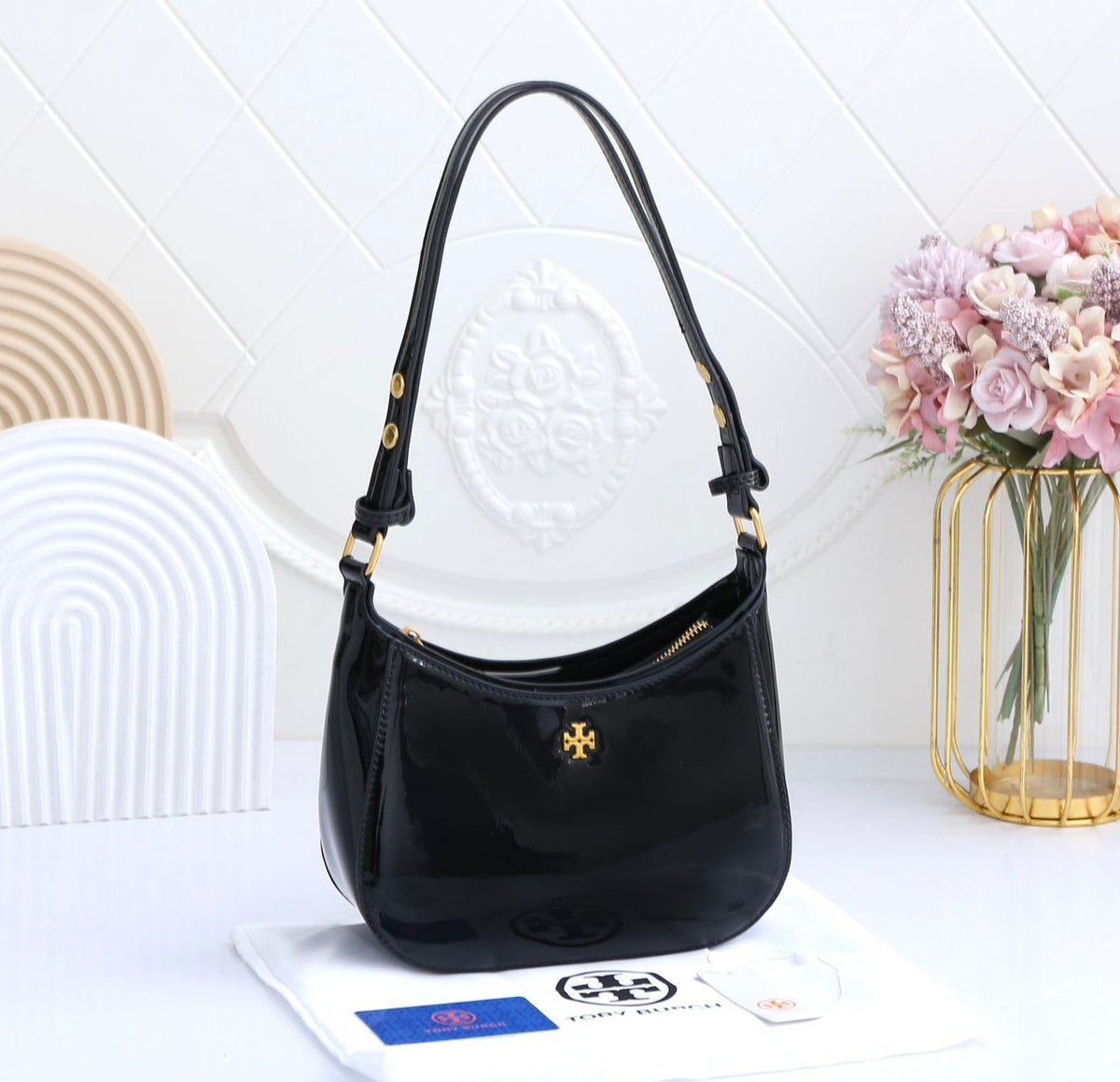 Black handbag on a white surface with a decorative background