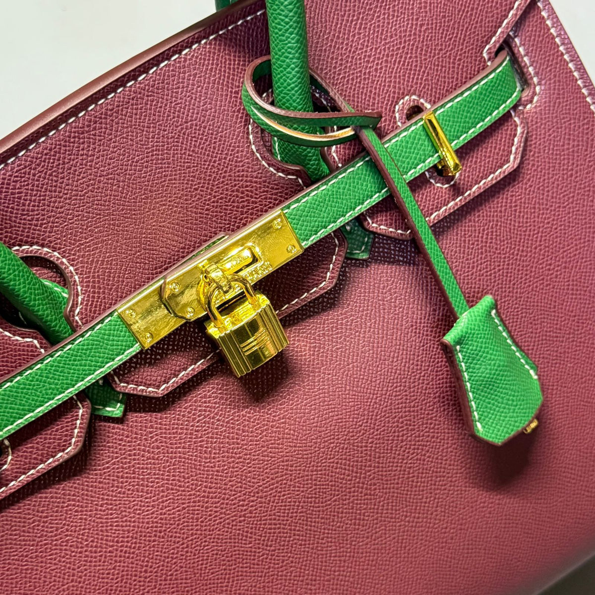 Front close up detail of burgundy and green luxury leather tote bag