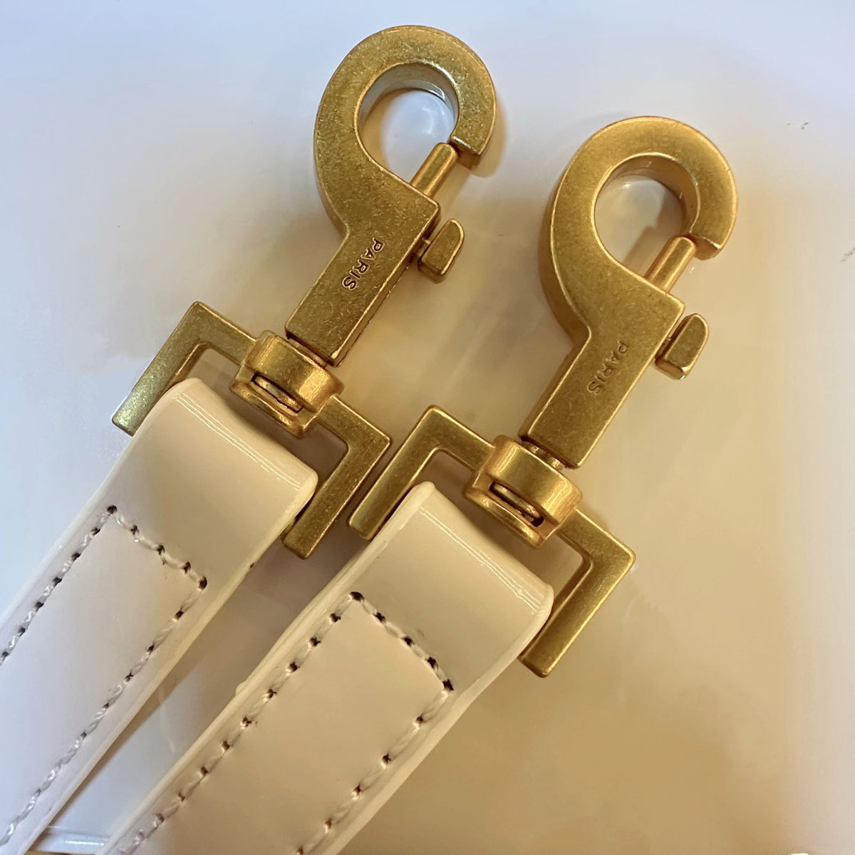 Close up of gold hardware clips on detachable leather shoulder strap